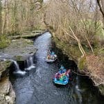 dingys on a river with groups of school pupils in it