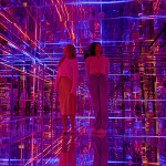 students in a glass room with various bright images and lights