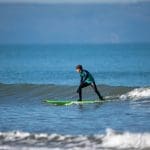 student surfing on a wave at the coast