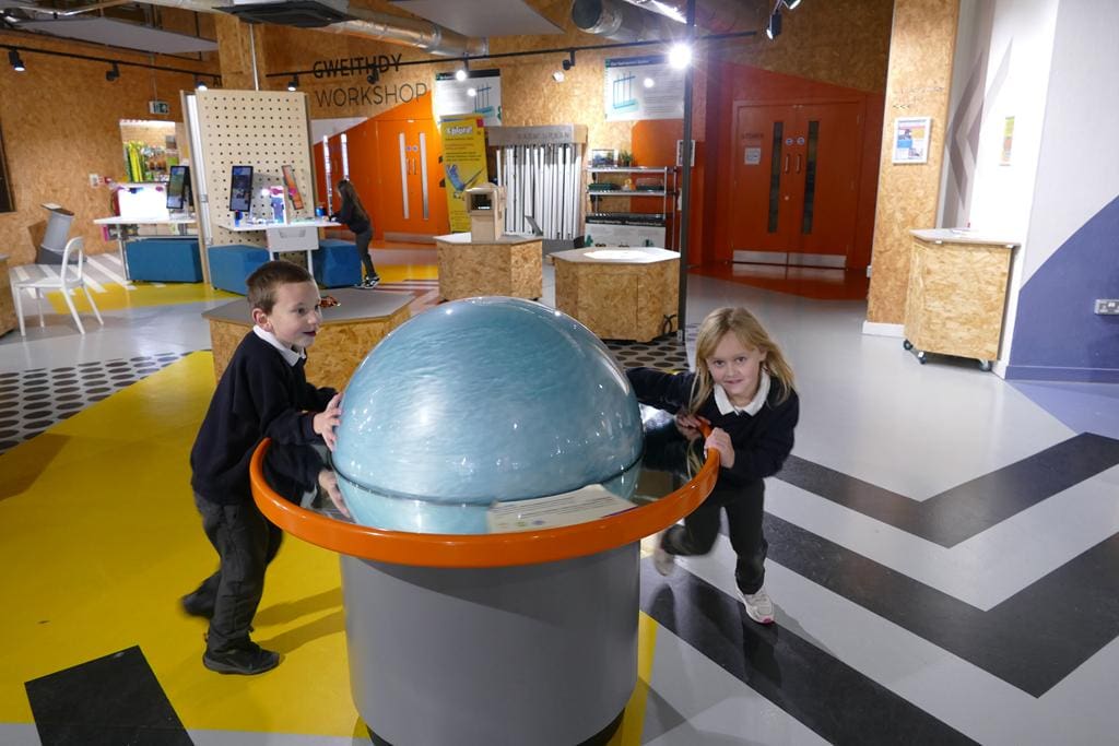 school pupils in a science exhibition room playing with immersive objects