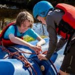two secondary pupils tying rope around plastic blue drums making a water raft to float in the water