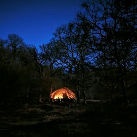 student in a tent at night with shining light in the countryside at night time