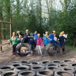 school group in hard hats near an outdoor assault course in the countryside