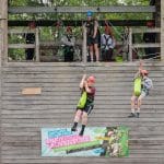 school students jumping off and zip lining off a tower outside