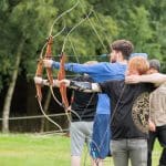 a group of pupils on a school trip doing archery