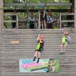 students going down a zip line from a tower