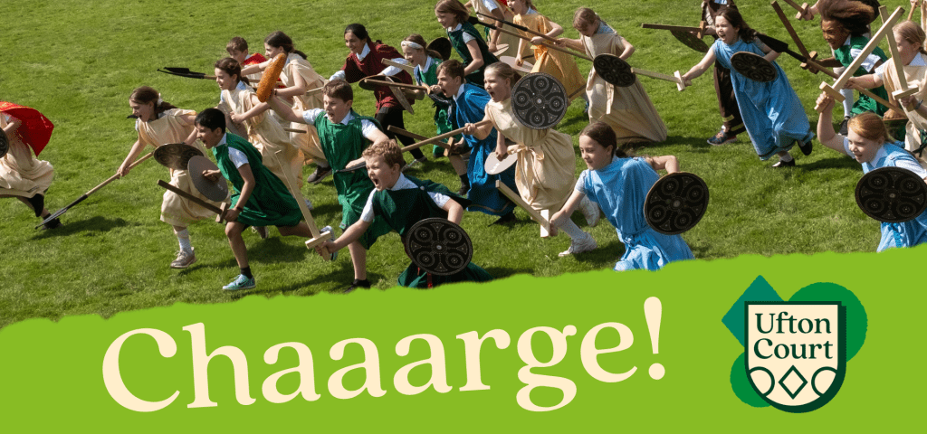 school children running in a field with Saxon dressing up clothes shields and wooden swords and spears