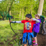 school student taking part in archery outside