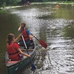 students in a kayak paddling on a river