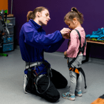 primary school child image with instructor helping with safety harness