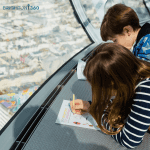 two school trip pupils on the I360 in Brighton drawing a picture of the landscape