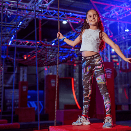 student holding a climbing rope and smiling at Ninja Warrior Leeds
