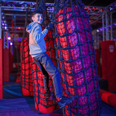 image shows school pupil climbing up on a climbing wall at Ninja Warrior Leeds