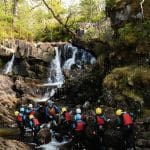 school trip group in hard hats and waterproofs doing gorge walking