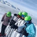 four school pupils in a line with skis and safety gear on