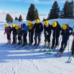group of school students in ski gear on a ski slope