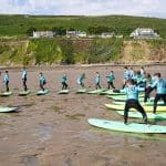 school pupils at the beach doing surf board training