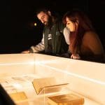 students looking at glass exhibition area with ancient books behind them