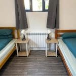 internal dorm room with beds and side tables near a window
