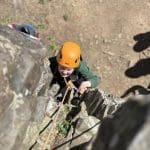 school pupil climbing up a cliff face in the Perthshire mountains