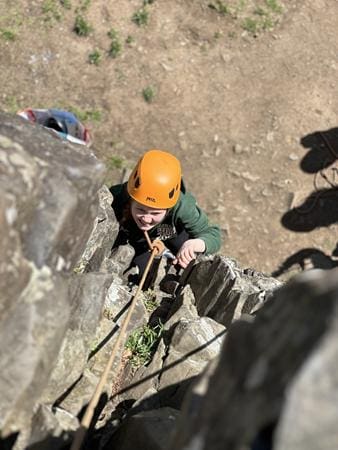 school pupil climbing up a cliff face in the Perthshire mountains