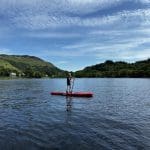 school pupil paddleboarding on a lake