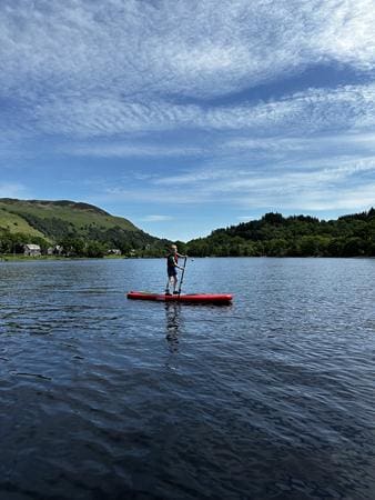school pupil paddleboarding on a lake