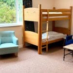 dorm room with bunkbeds chairs and a table