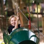 primary pupil in a zip car at a high ropes adventure outdoor course