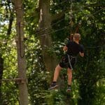 school pupil high up in the trees zip lining