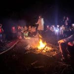 school group around an open fire pit at night outside