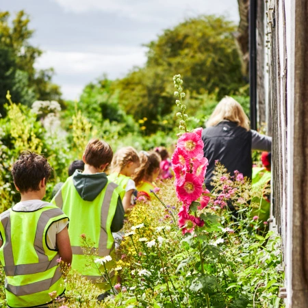 school group outside in high vis vests walking along a Tudor garden