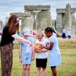 primary school group looking at an artifact handed by a teacher