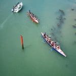 pupils in long canoes paddling down a river