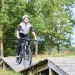 school pupil on a BMX going over a wooden bridge on a countryside track