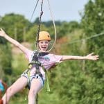 school pupil on a zip wire waving and smiling