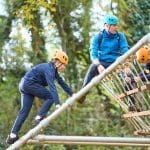 pupils climbing an activity wooden frame in the woods