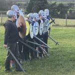 secondary school pupils in a line dressed as viking raiders with play shields helmets and swords