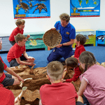 school pupils in study room with guide learning about animal history facts